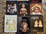 quatre livres posés par terre, avec des images de poupées dessus