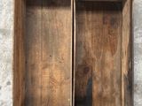 an old wooden box with two open compartments sitting on a concrete surface