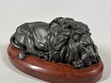 an image of a statue of a lion laying on top of a wooden base