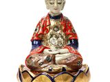 statue of a buddha sitting on a lotus flower with a cat in his lap