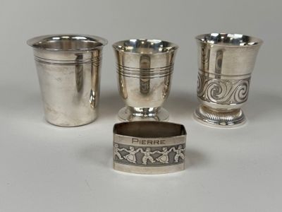 trois tasses en argent et un porte-serviette posés sur une table