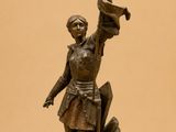 bronze statue of a man holding a flag and a sword