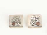 pair of silver and copper cufflinks with a design of circles and circles