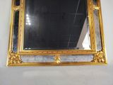 a mirror hanging on the wall with a gold frame
