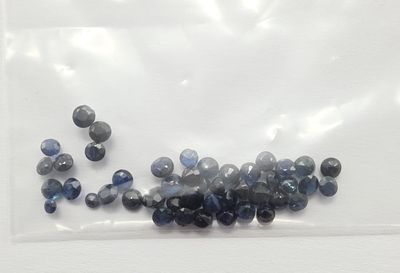 un sachet de perles bleues et noires posé sur une surface blanche