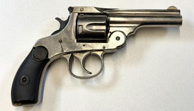 revolver posé sur une surface blanche, avec une crosse et une poignée noires