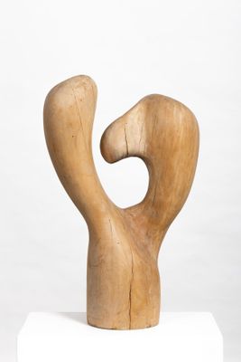 sculpture of a wooden figure on a white pedestal against a white background
