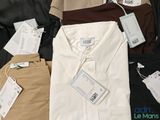several men ' s shirts are laid out on a bed with tags on them
