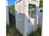 des toilettes portables blanches posées dans l'herbe, près d'une clôture