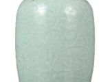 un vase vert posé sur une surface blanche