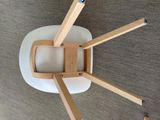 a white chair with wooden legs on a carpeted floor