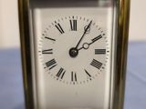 une petite horloge en or avec des chiffres romains