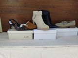 Plusieurs paires de chaussures pour femmes sont posées sur des cartons, sur un lit.