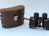 a brown bag and a pair of binoculars on a white surface