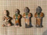 Trois figurines représentant des personnes d'origine asiatique sont assises sur une nappe à carreaux.