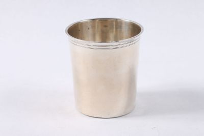 une tasse en argent posée sur une surface blanche