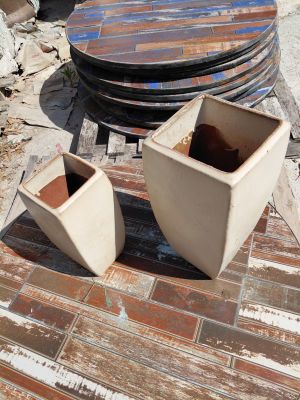 two white vases sitting on a table next to a stack of plates