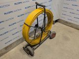 a yellow hose on a cart next to a wall