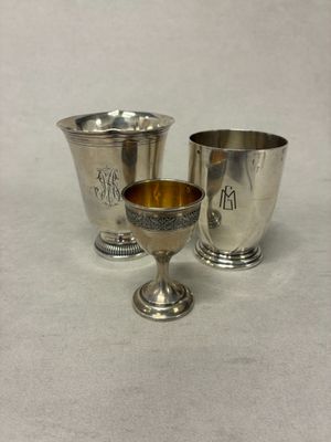 deux tasses en argent et une tasse en argent posées sur une surface blanche
