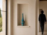 un homme qui traverse une pièce avec un vase