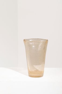 un petit verre posé sur une surface blanche