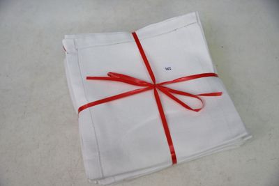 a white napkin with a red ribbon wrapped around it