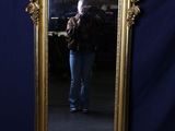 un miroir à cadre doré dans lequel on voit un homme en train de se prendre en photo