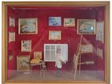 a picture of a man standing in front of a display of paintings