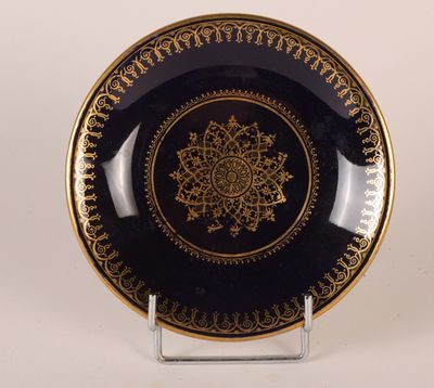 une assiette noire et dorée ornée d'un motif doré