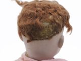 a close up of a doll ' s head with a pink dress