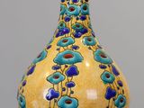 un vase jaune orné de fleurs bleues, posé sur une table