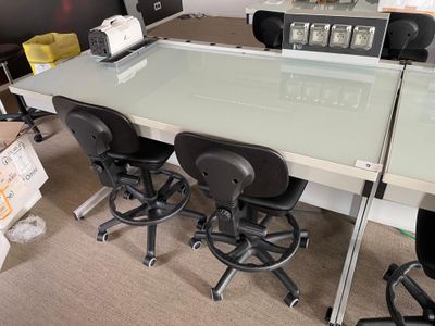a glass table with four chairs in the middle of the room