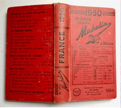 an old red book sitting on top of a table next to a white table
