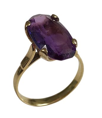 gros plan d'une bague en or avec une pierre violette