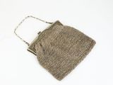 beige purse on a white surface with a chain hanging from it