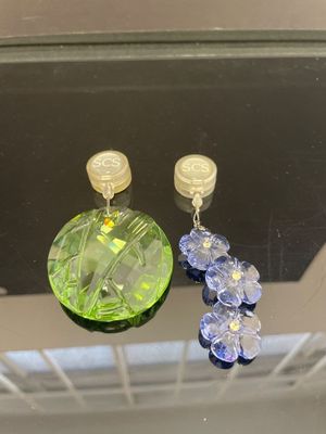 des boucles d'oreilles en cristal vert et bleu suspendues à un miroir dans une pièce