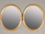 a pair of oval mirrors with a gold frame