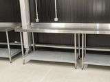 une cuisine équipée de plans de travail en inox et d'un réfrigérateur