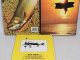 two books on a table with a man in a boat and a fish
