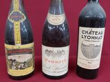 three bottles of wine are lined up on a red surface