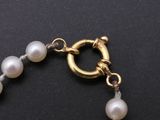 a close up of a bracelet with pearls on a black surface