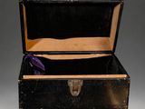 a small black box with a purple ribbon and a key in it