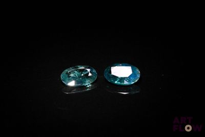 une paire de pierres précieuses de topaze bleue sur un fond noir