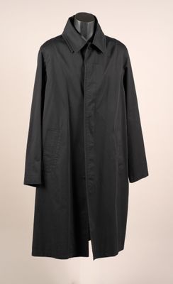 un manteau noir suspendu à un cintre sur un mur blanc