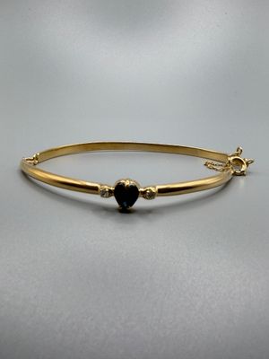 un bracelet rigide en or orné d'un cœur noir
