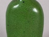 a green vase with a black lid sitting on a table