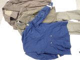 a pile of clothing on a bed with a blue jacket