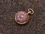 un gros plan sur une boucle d'oreille en or sertie de pierres roses et blanches