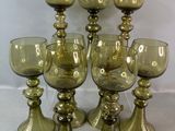 six verres à pied en verre vert, portant des numéros, posés sur une table