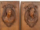 pair of carved wood plaques depicting a woman and a man